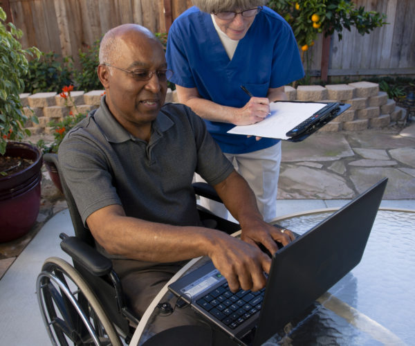 Healthcare-worker-helping-disabled-senior-with-computer