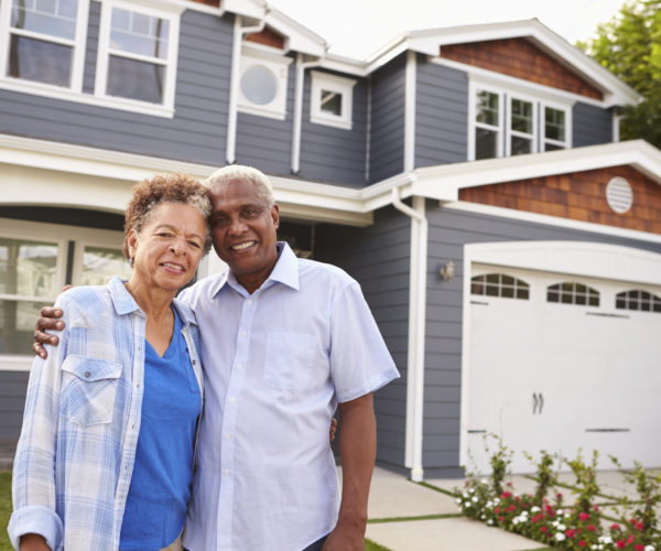 Senior-african-american-couple-standing-outside-a-large-suburban-house